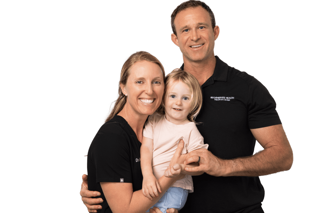 Two adults in RHMC uniforms holding a small child, smiling in a family portrait.