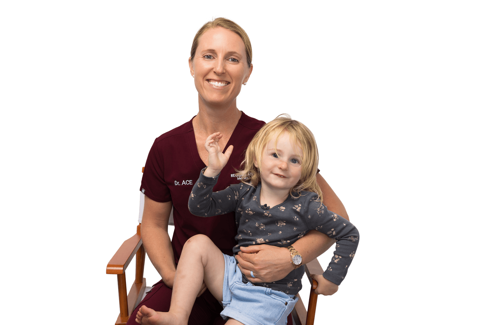 Medical provider holding a small child while both smile in a seated family portrait.