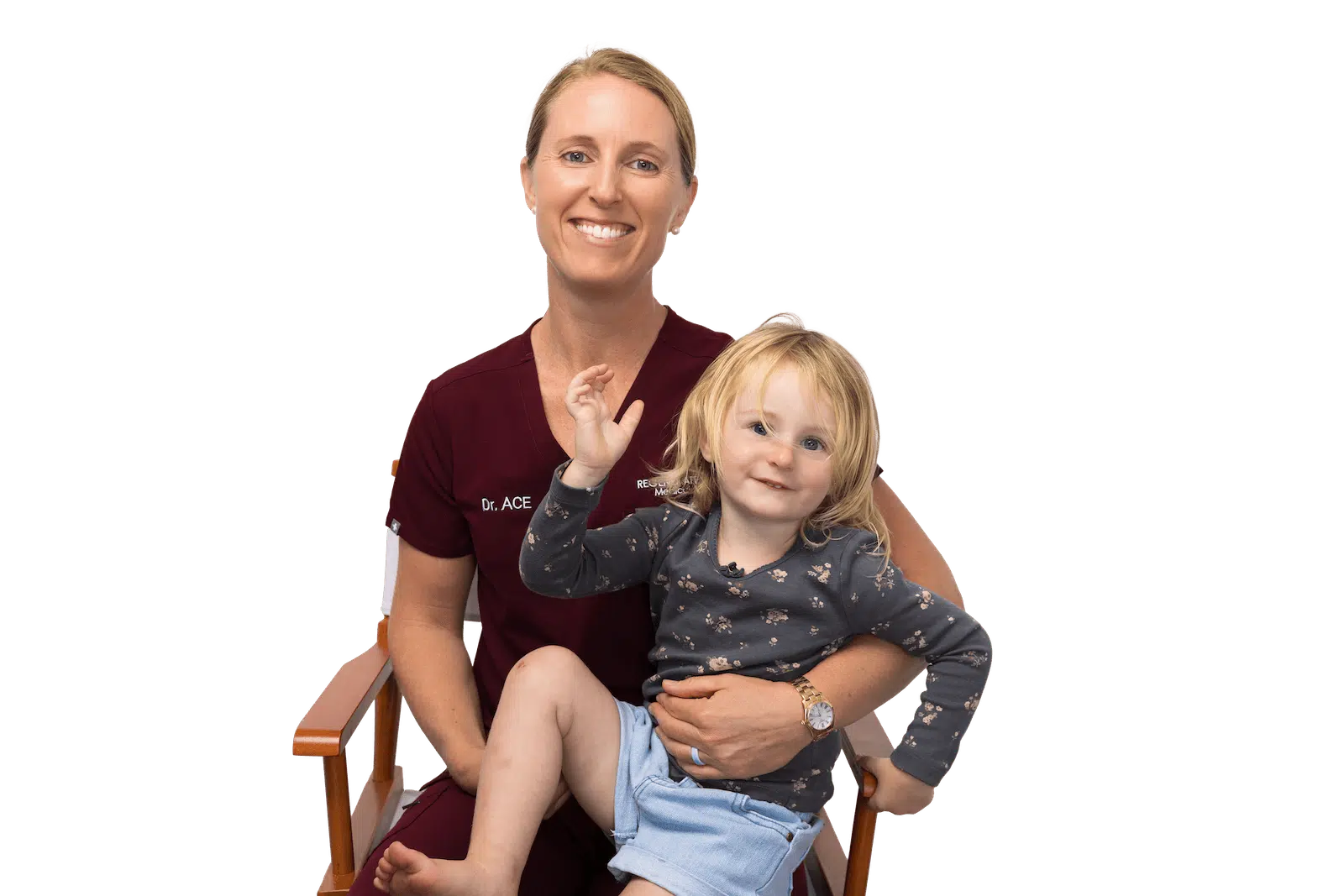 Medical provider holding a small child while both smile in a seated family portrait.