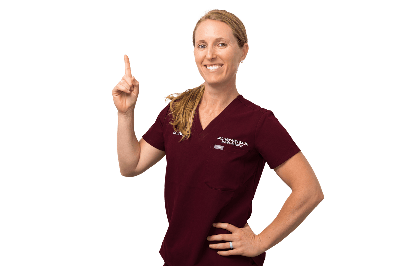 Female medical provider in burgundy scrubs smiling and posing with one hand on hip.