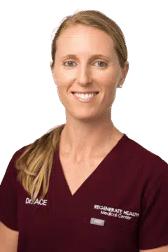 Medical practitioner in burgundy scrubs smiling in a vertical staff headshot