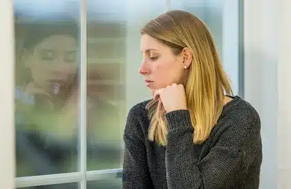 Tired woman sitting by a window and reflecting on her health