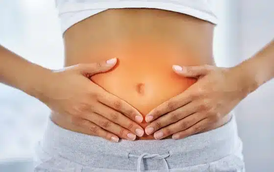 bloating-gut-symptoms Woman holding her stomach with visible bloating and abdominal discomfort
