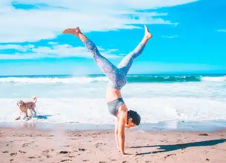 Woman doing a yoga handstand on the beach, representing overall strength and health